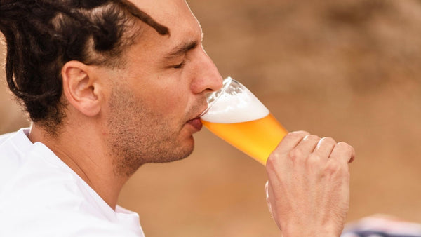 Man drinking a glass of East Forged Nitro Tea outside setting in the park